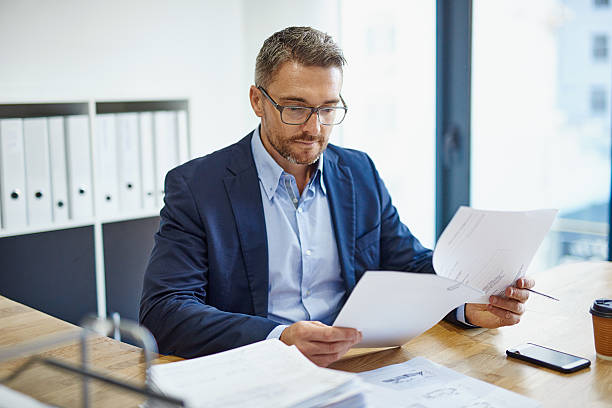 A businessman in an office reviews documents related to tariffs and import restrictions in Dubai.